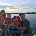 Violet, 5, Emmet, 3, Oliver, 2, and dad Gord Buxton pose with a largie on the Bay of Quinte.