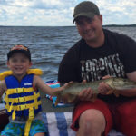 Nate Sharp, 4, with some help from his dad, holds his first fish that he caught on the Ottawa River.