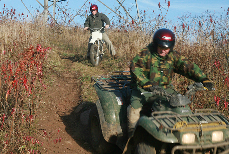 men riding ATV and dirt bike down a hill