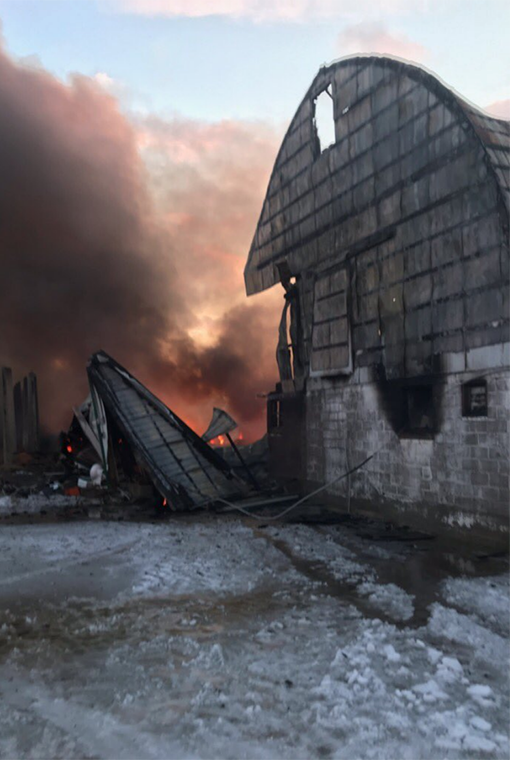 a burned barn is choked in lingering flames