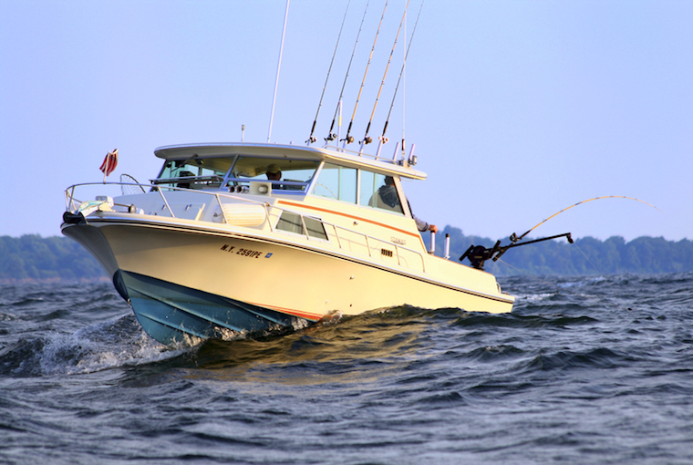 a boat with fishing lines roars through the water