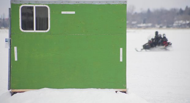 a green ice hut on a lake