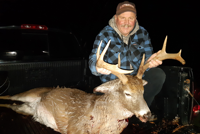 Hunter with a white-tailed deer in the back of a truck