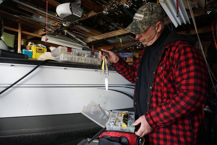 Man holding tangled fishing line and lured in his garage