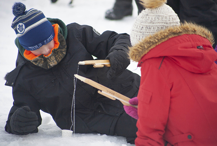 Children ice fishing with jigging sticks