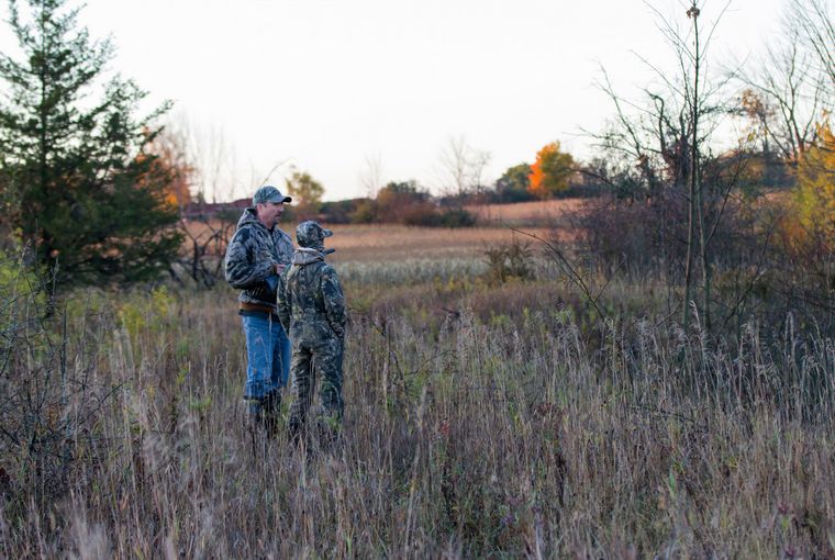 Mentor and apprentice hunting standing in a field at dusk/dawn