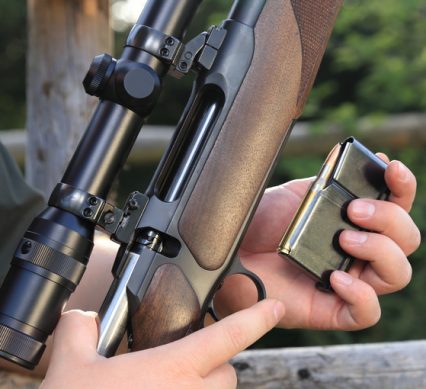 A Hunter loading his hunting rifle gun with magazine
