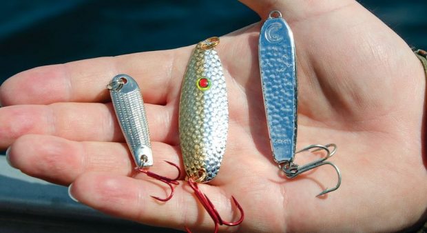 heavy weighted fishing spoons in an anglers hand