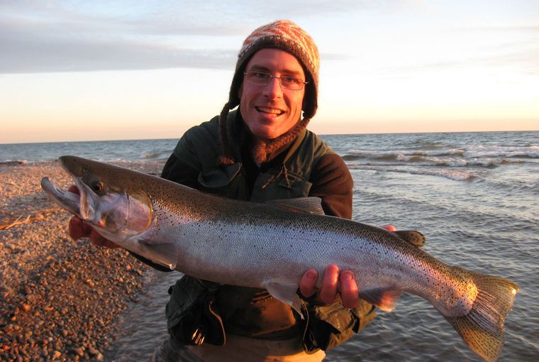 Angler holding steelhead at sunset