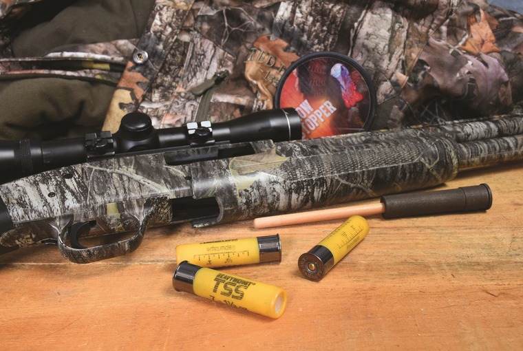 20 gauge camo patterned shotgun on a table with shogun shells and a slate turkey call.