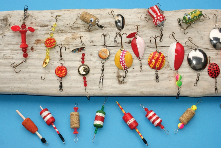 Various homemade fishing lures displayed on a piece of drift wood. 