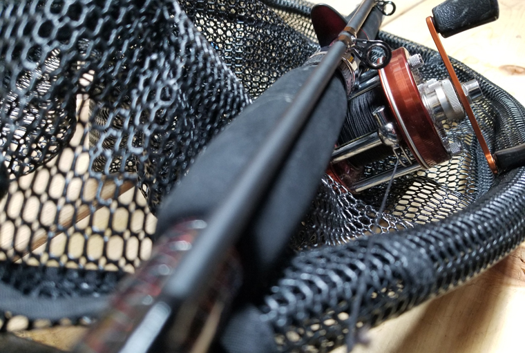 fishing rod and fishing net sitting on a bench