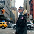 a man turns his head at a busy Toronto crosswalk, wearing a Canada Goose coat
