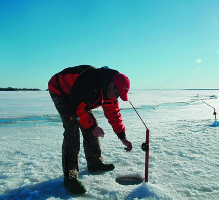 an ice angler checking a tip up