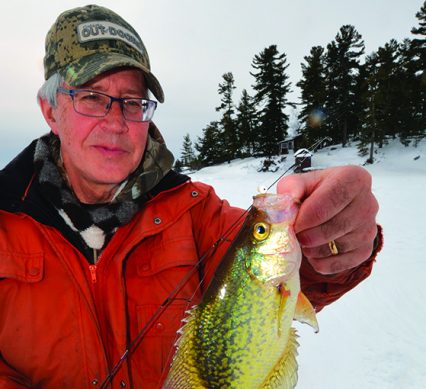 a man is ice fishing for crappie