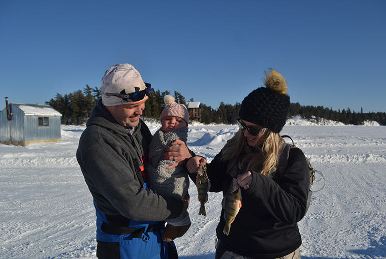 a trio hold some perch on the ice