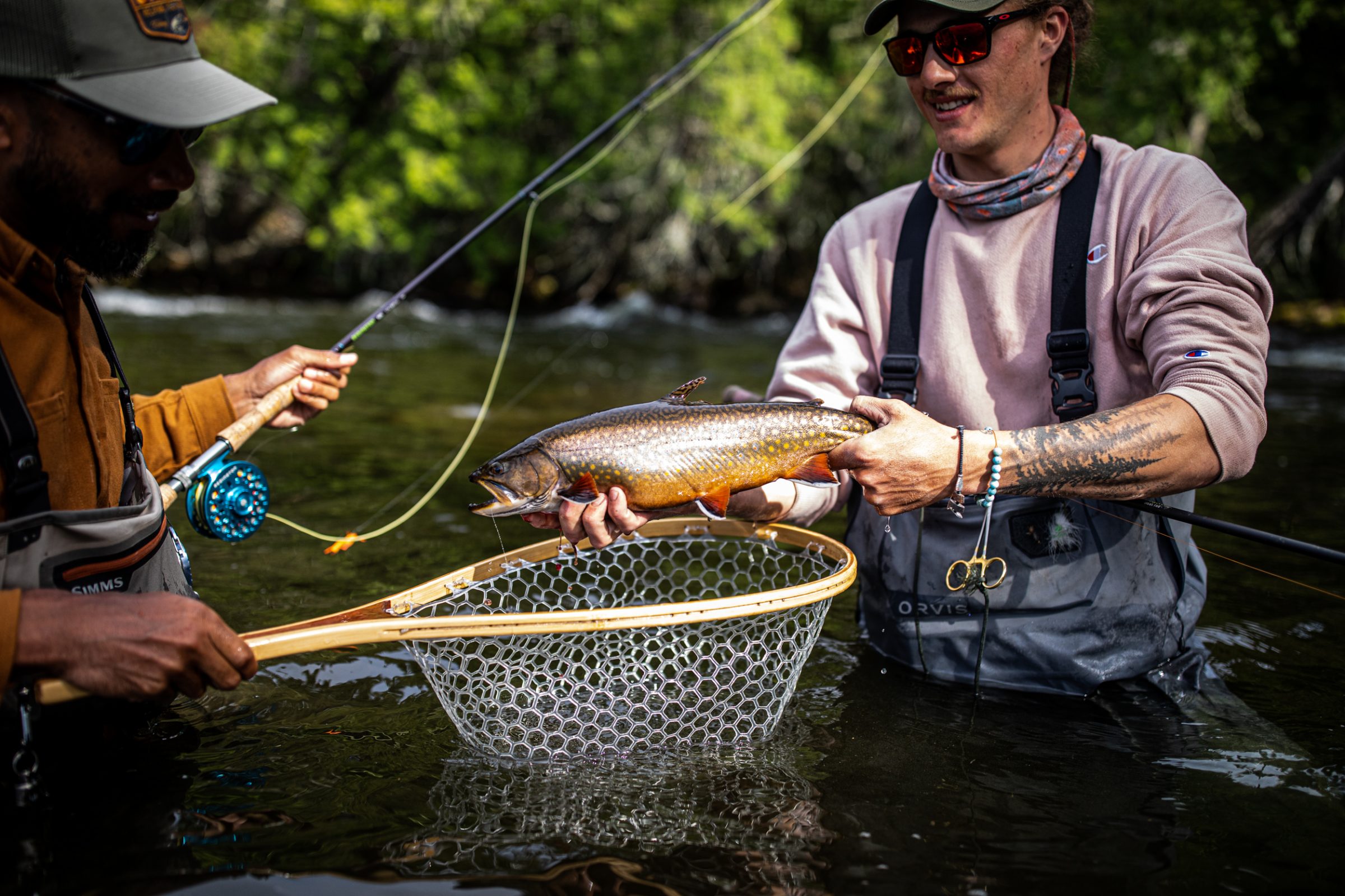 two anglers holding a brook trout