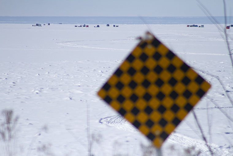 An ominous hazard sign looks out among the ice huts