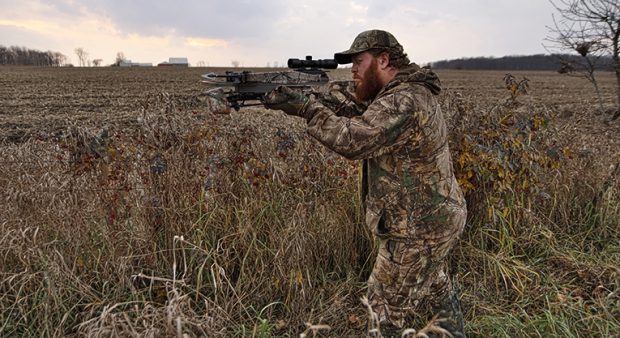 bowhunter takes aim in a field