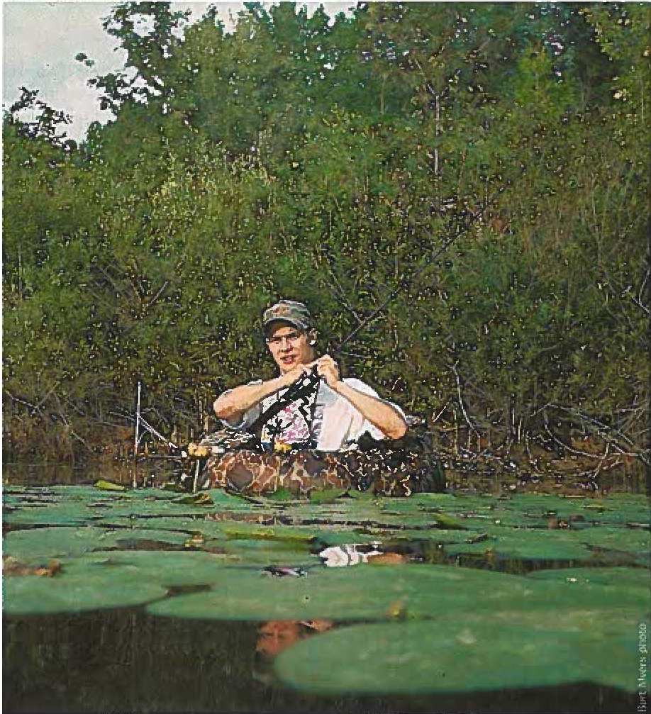 Justin Hoffman in an inner tube, fishing among lily pads
