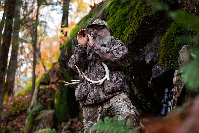 man in camo, drawing whitetails using deer call