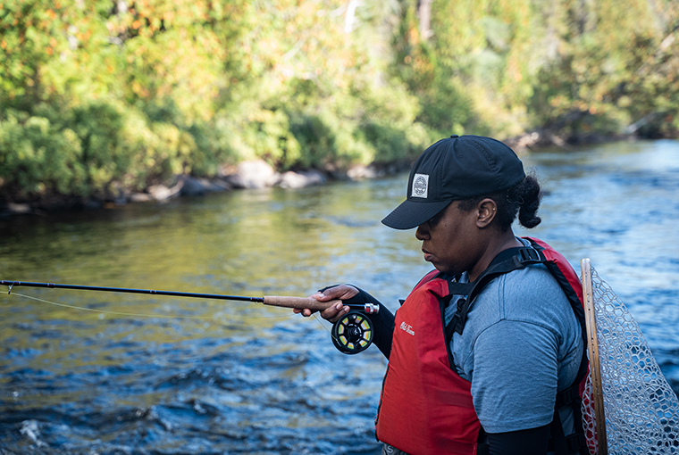 Demiesha Dennis of Brown Girl Outdoor World holding a fly rod in a river