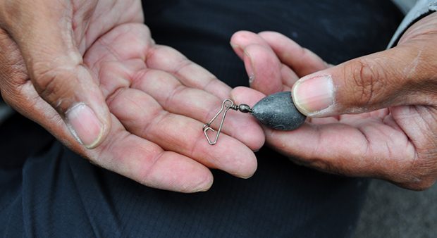 a man holds a sinker in weathered hands