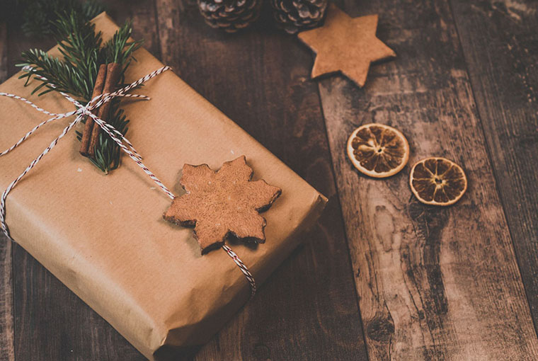 a wrapped burlap and string gift with wood-cut ornaments and delightful dried oranges, sprig of coniferous