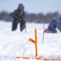 two kids on the ice partaking of some hard water fishing