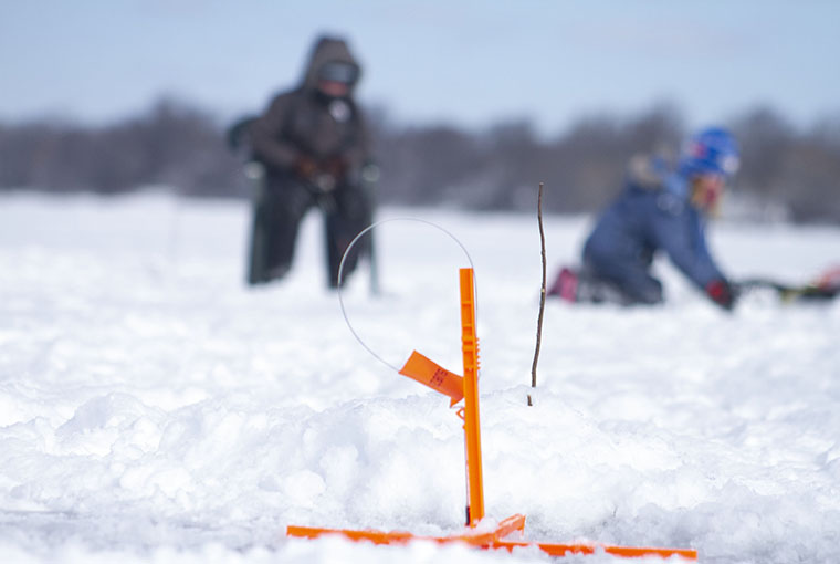 two kids on the ice partaking of some hard water fishing