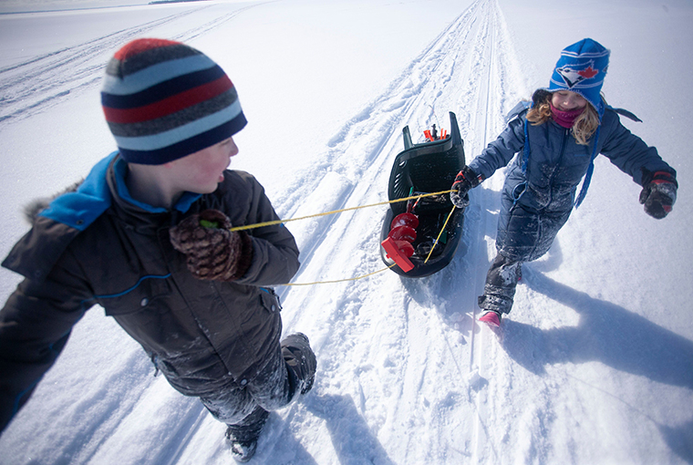 kids pulling ice fishing gear in a sled